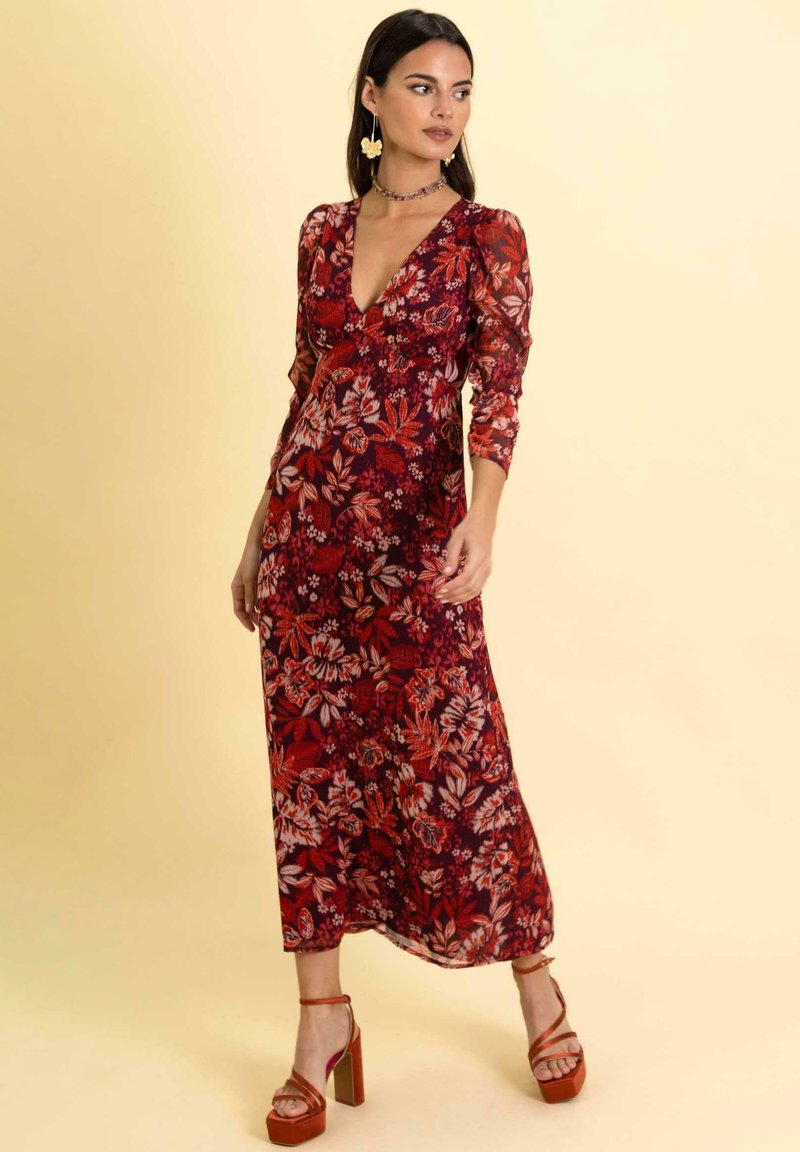 Langes Blumenkleid mit tiefem V-Ausschnitt, langen Ärmeln und tailliertem Oberteil. Besitzt ein rot-rosa Blumenmuster auf dunklem Hintergrund.