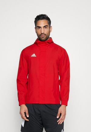 Rote leichte Jacke mit Kapuze, elastischen Bündchen, Reißverschluss und weißem Logo auf der linken Brust. Glatte Textur und einfaches Design.