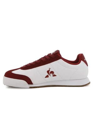 Scarpa da ginnastica bassa bianca e rosso scuro con logo laterale, chiusura con lacci e suola bianca con battistrada marrone chiaro.