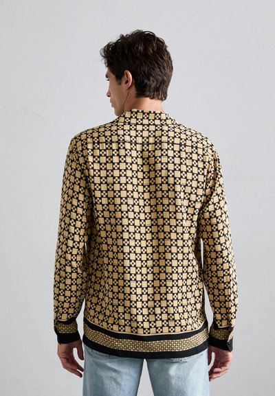 Langsleeve shirt in zwart en beige geometrisch patroon, met een losse pasvorm, knoopmanchetten en een rechte zoom, gemaakt van lichtgewicht stof.