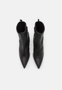 Schwarze Leder-Stiefeletten mit spitzen Zehen, glatter Textur, seitlichen Reißverschlüssen und einer figurbetonten Silhouette.