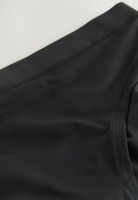 Pantaloni corti in tessuto nero con una texture liscia e elastica. Presentano cuciture piatte e un design aderente, adatti per varie attività.
