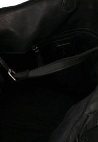 Zwarte leren handtas interieur met een gladde textuur, een ritszak en een afneembare schouderriem met een zilveren hardware detail.