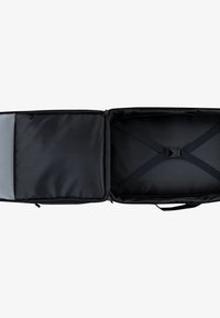 Fekete kézipoggyász tágas belső térrel, keresztpántokkal az értékek rögzítéséhez és egy hálós zsebbel az egyik oldalon a rendezés érdekében.