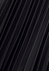 Gros plan d'une surface noire texturée avec des crêtes diagonales surélevées, régulièrement espacées, créant un motif sur le matériau.