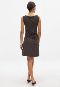 Braunes ärmelloses Kleid mit einem drapierten Ausschnitt und gerafften Details auf der Rückseite, mit geradem Saum und glatter Stoffstruktur.