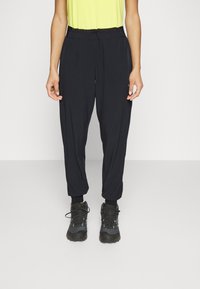 Svarta, lätta joggingbyxor med avsmalnande ben, elastisk midja och sidofickor, kombinerat med svarta vandringsskor.