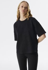 Camiseta negra de manga corta con textura en relieve y el patrón "ONE BLUE MOON", cuello redondo y corte relajado.