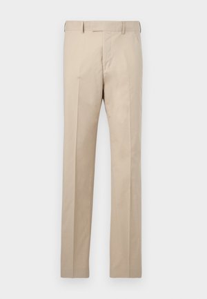 Bež hlače s pravimi nogavicami, pasovi za pas, sprednja zadrga in gube na enobarvnem ozadju.