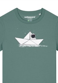 Groene katoen t-shirt met een witte grafiek van een papieren boot met een astronaut. Het ontwerp bevat sterren en golven, wat de visuele aantrekkingskracht vergroot.