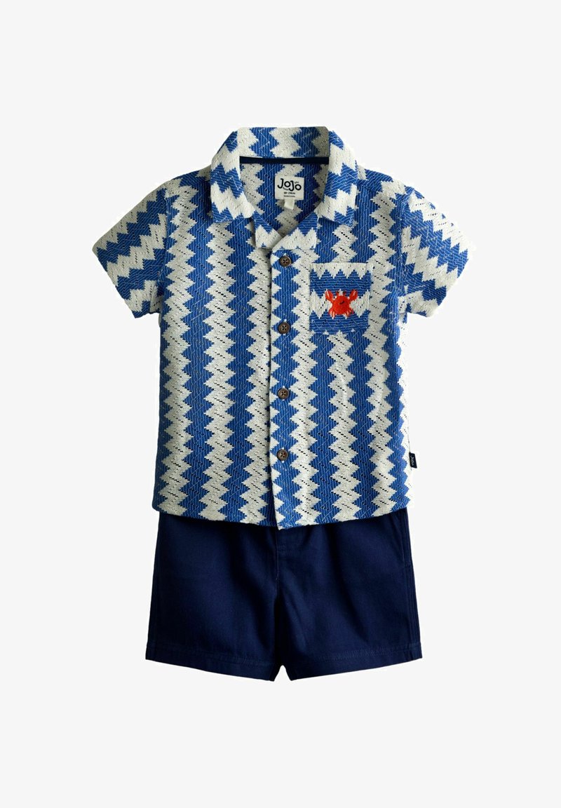 Tøj til småbørn med blå og hvide zigzag-mønstrede kortærmede skjorte med en rød krabbe på lommen, kombineret med ensfarvede marineblå shorts.