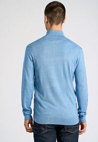 Jasnoniebieski sweter z długim rękawem, wykonany z miękkiego dzianinowego materiału. Posiada wysoki kołnierz i dopasowany krój, z prążkowanymi mankietami i dołem.