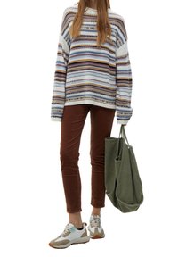 Gestreepte gebreide trui in wit, blauw en paars; bruine corduroy broek; witte en beige sneakers; olijfgroene tote bag.