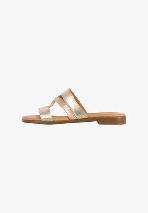 Sandale en métal doré avec deux brides parallèles, semelle plate et semelle intérieure beige. Texture lisse avec un minimalisme dans les détails et un design décontracté.