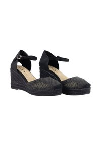 Zapatos de esparto negros con cuña, suela de yute trenzado, textura tejida y una correa de tela en el tobillo asegurada con una hebilla de tono plateado.