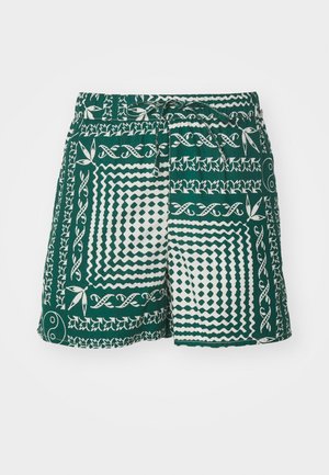 Grønne shorts med hvite mønstre inkludert geometriske former og blomsterdesign. Har snor i midjen og en avslappet passform.