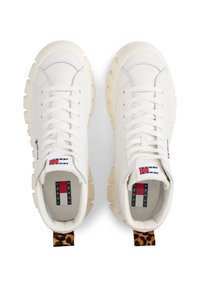 Baskets en cuir blanc avec de épaisses semelles beiges, dotées d'un empiècement en imprimé léopard à l'arrière et d'une étiquette de marque en rouge, blanc et bleu à l'intérieur.