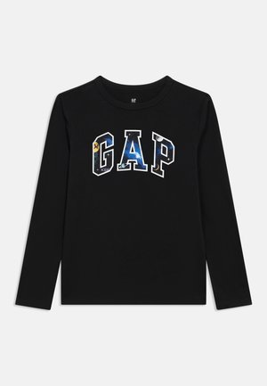 Chemise noire à manches longues avec le mot GAP en grandes lettres blanches encadrées remplies d'un motif sur le thème de l'espace comprenant des étoiles et des planètes.