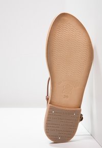 Hnědé sandály s hladkou, plochou podrážkou s vlnkovou texturou. Obsahují značkový design a velikost 39 vyrytou na spodní straně.