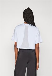 Kortärmad ljusblå t-shirt med nätpanel på ryggen, avslappnad passform, tillsammans med svarta träningsbyxor.