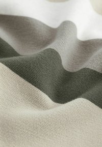 Tejido de punto con franjas onduladas alternas en suave beige, verde apagado y colores crema, con una textura suave y un sutil brillo.