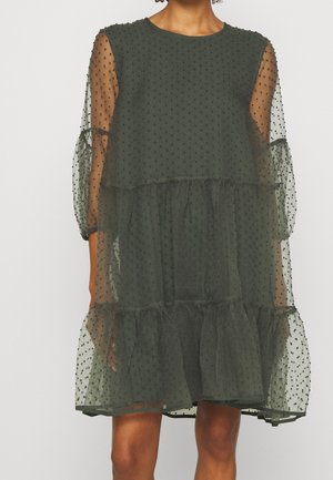 Przezroczysta sukienka w ciemnozielonym kolorze w groszki, z warstwami falbanek i bufkami na trzy czwarte rękawa, na gładkiej podszewce.