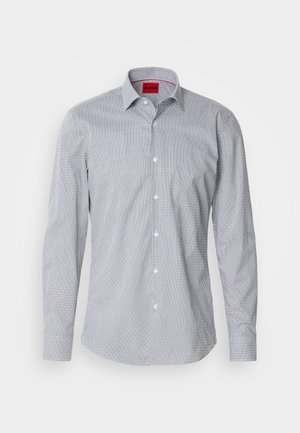 Chemise légère à manches longues avec un motif géométrique blanc et bleu marine, col à boutons et une étiquette logo rouge au niveau du cou.