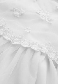 Witte tule stof met bloemrijke borduursels langs de zoom, met delicate ruches en een zachte, doorschijnende textuur.