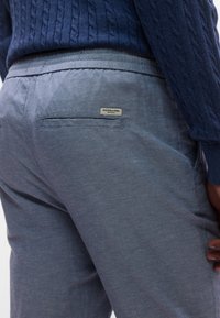 Φωτεινά γαλάζια, υφασμάτινα παντελόνια με υφή, με πίσω τσέπη και μικρή ετικέτα μάρκας. Η μέση είναι ελαστική για άνεση.