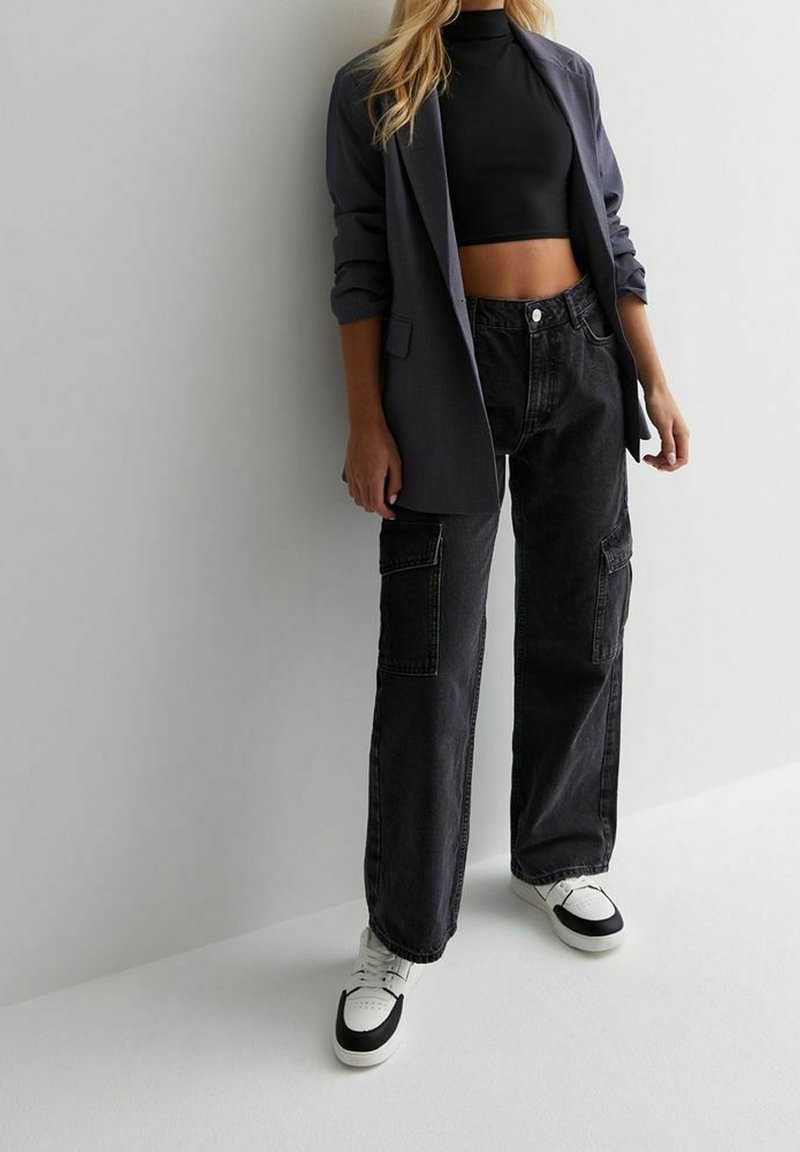 Mustapaita, joka on yhdistetty väljäntuntuisen harmaan bleiserin, farkkukangaspussihousujen ja musta-valkoisten lenkkareiden kanssa. Teksturoitu, rento ja moderni muotoilu.