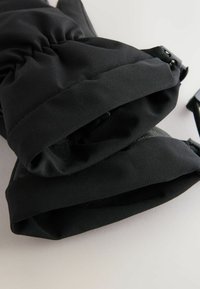 Guanti isolanti neri con tessuto liscio, polsini elastici e cinturini regolabili per una vestibilità sicura. Dotati di una morbida fodera interna.