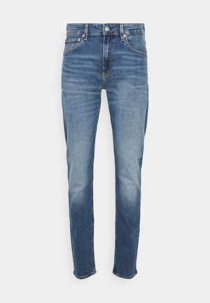 Modré denimové džíny s úzkým střihem, s zipovým zapínáním, pěti kapsami a mírným vyblednutím na stehnech a lemu. Na spodním okraji jsou pracovní ostré řez.