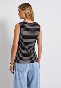 Svart och vit randig ärmlös topp med ribbat mönster, har rund halsringning och en åtsittande silhuett bak.