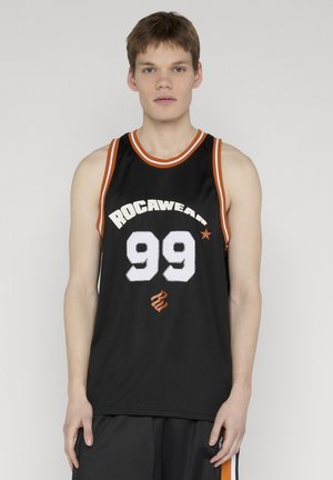 Młody mężczyzna w czarnym koszykarskim trykocie Rocawear z numerem 99 i pomarańczowo-białym wykończeniem, stojący na jednolitym tle.