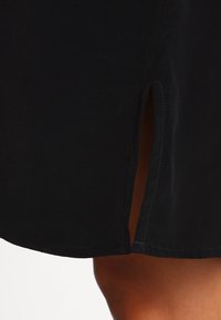 Czarna spódnica z bocznym rozcięciem. Wykonana z gładkiego materiału o prostym kroju i prostym wykończeniu. Minimalistyczny design bez wzorów ani ozdób.