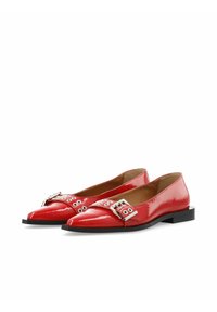 Ballerine in vernice rossa con punta affusolata, caratterizzate da una fibbia decorativa e fori circolari su una fascia ampia. Suola nera piatta.