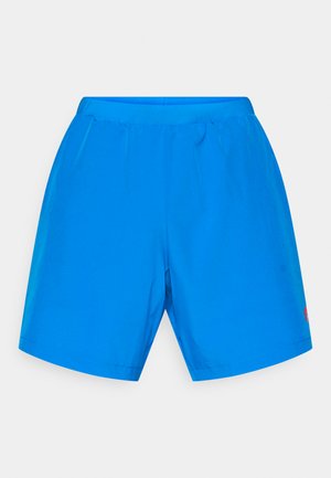 Sinised spordilühikesed püksid elastse vöökoha, sileda tekstuuriga, sirge lõikega ja väikese punase logoga alumisel paremal serval.