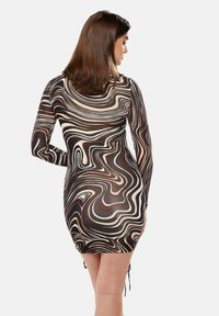 Long-sleeve, bodycon dress featuring a swirling brown, cream, and black pattern. The fabric is sheer with drawstring accents at the hem.