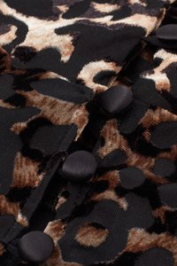 Tissu en velours avec un motif léopard noir et marron, agrémenté de boutons noirs lisses. Surface texturée avec divers motifs animaliers.