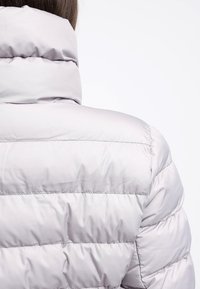 Giacca puffer grigia chiara con colletto alto, design trapuntato con cuciture orizzontali e texture liscia e lucida.