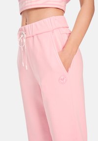 Rosa Jogginghosen mit entspannter Passform, weichem Baumwollmaterial, elastischem Bund mit Kordelzug, Seitentaschen und einem Logo-Patch.