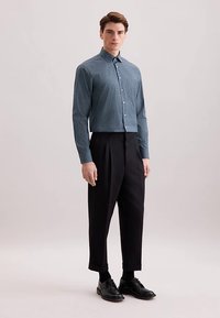 Blauw patroon overhemd met knopen en lange mouwen, gecombineerd met een hoge taille zwarte broek en zwarte nette schoenen. Soepele stof en nauwsluitende pasvorm.