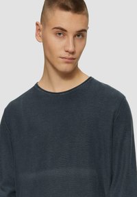 Donkerblauwe blouse met lange mouwen en een ronde halslijn, gemaakt van een zachte, gestructureerde stof, met minimale naden en een ontspannen pasvorm.