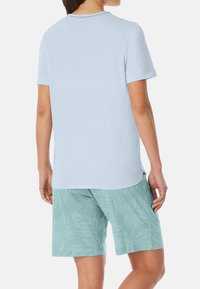 Camiseta azul claro de manga corta, diseño liso. Combina con pantalones cortos verde menta con un sutil patrón de hojas.