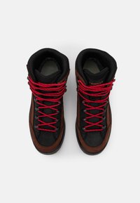 Braune und schwarze High-Top-Stiefel mit roten Schnürsenkeln, ausgestattet mit einem strukturierten Obermaterial und einem gepolsterten Kragen für zusätzlichen Halt. Dual-Material-Design für Langlebigkeit.