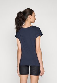 Mörkblå kortärmad t-shirt med en avslappnad passform, tillsammans med svarta shorts med en subtil leopardtryckstextur.