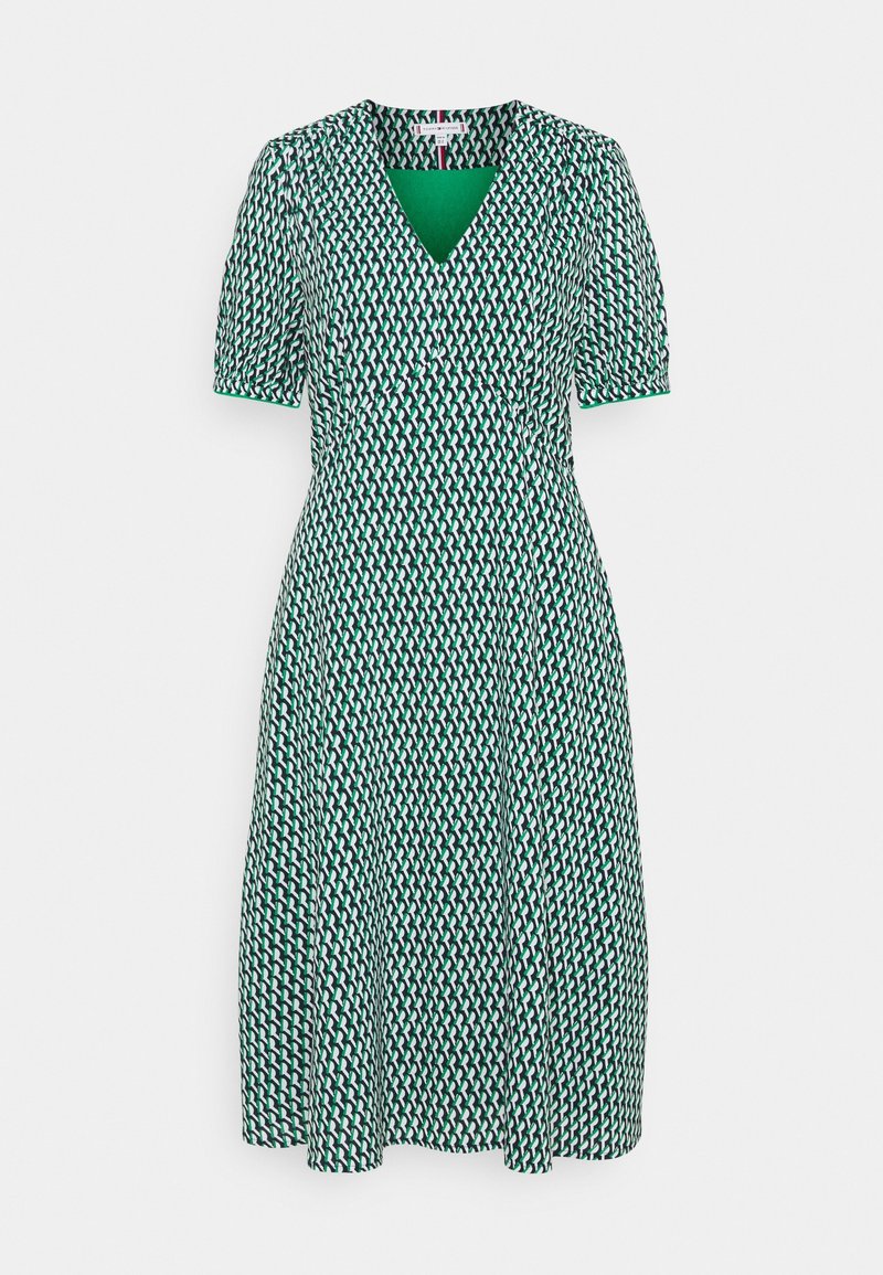Vihreä ja valkoinen kuvioitu mekko, jossa on V-pääntie, lyhyet hihat, istuva yläosa ja virtaava hame. Valmistettu kevyestä kankaasta.