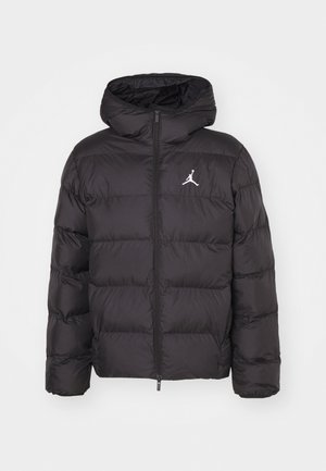 Doudoune noire avec capuche, équipée d'une fermeture éclair frontale, d'un design matelassé et d'un logo Jumpman blanc sur la poitrine. Matière lisse et brillante.