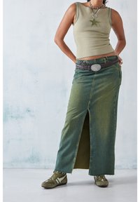 Grön denim maxikjol med en slits framtill, kombinerad med en ribbad olivfärgad linne och ett flätat brunt bälte med runt silverbuckle.