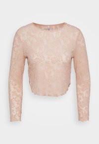 Světle růžový krajkový crop top s dlouhými rukávy, vlnitým lemem, květinovým vzorem a kulatým výstřihem. Průsvitná textura dodává jemný detail.